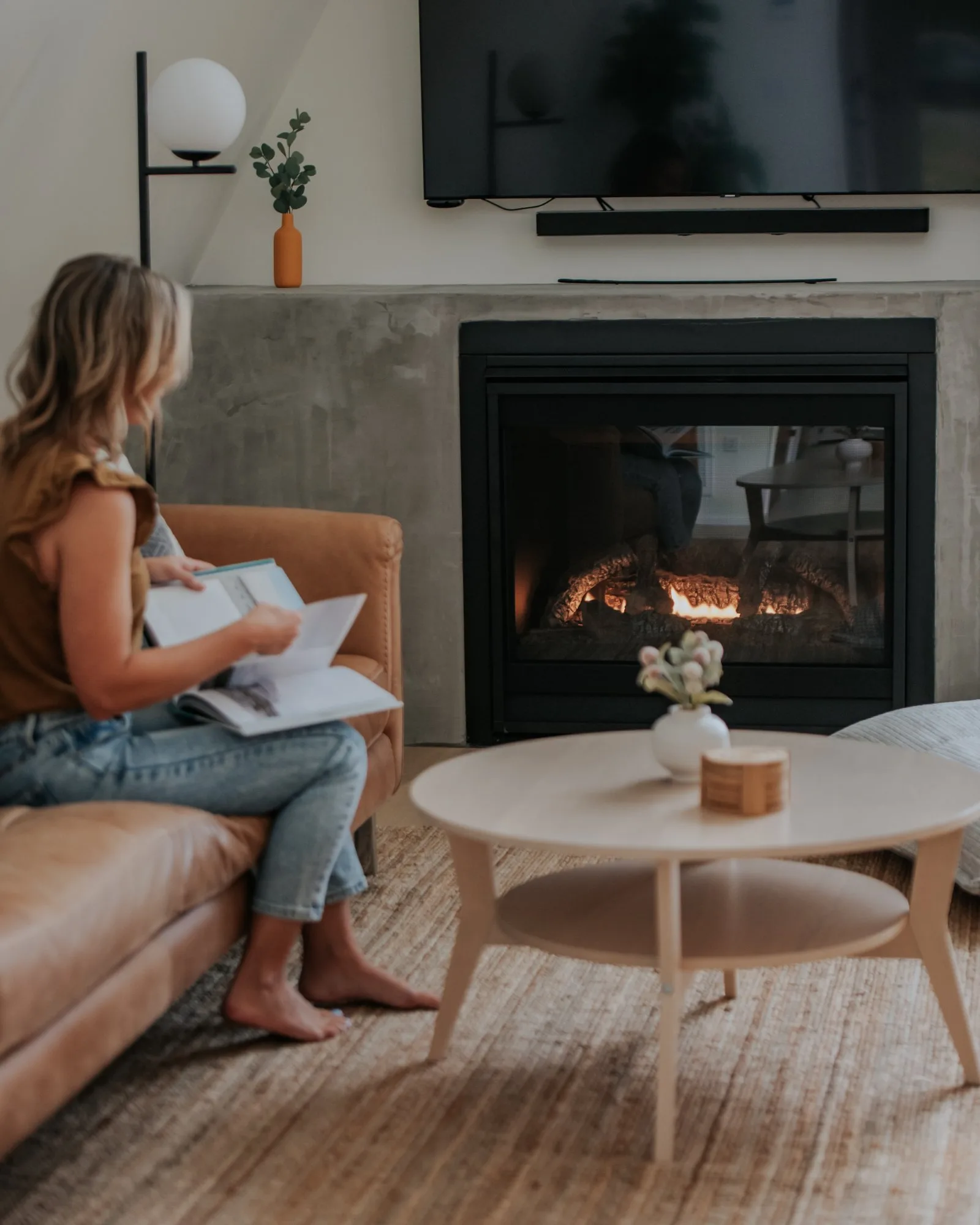 Woman reading by the gas fireplace at The A-Frame luxury cabin on the Cumberland Plateau